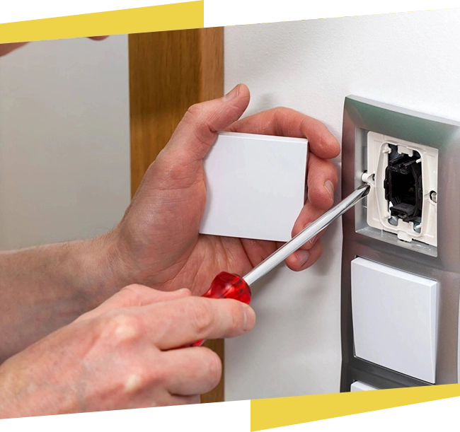 A person is holding a screwdriver and installing an electrical outlet.